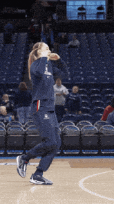 a female basketball player stands on a court in front of an empty stadium that says coleman on the sidelines