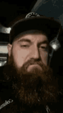 a man with a beard is wearing a hat and making a face .