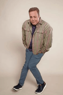 a man in a plaid shirt and blue pants is standing with his hands in his pockets