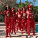 a group of men dressed in red devil costumes are standing next to each other in front of a pool .