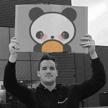 a man holding up a cardboard box with a panda face on it