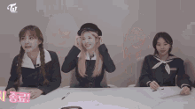 three girls are sitting at a table with the letters twice on the bottom