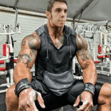 a man with a tattoo on his arm sits in a gym