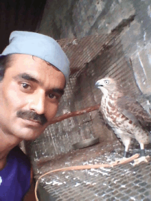 a man wearing a blue hat stands next to a bird