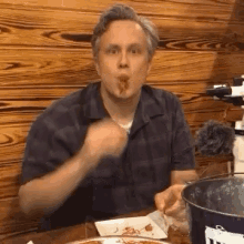 a man is sitting at a table with a plate of food in front of him and a bucket with the word t on it