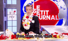 a man wearing a lei stands in front of a sign that says " le petit journal "