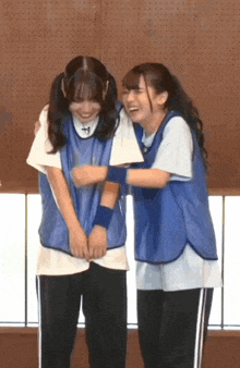 two girls in blue vests are hugging each other