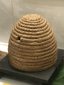 a wicker beehive sits on a black table