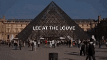 a crowd of people are gathered in front of a pyramid with the words lee at the louvre written on it