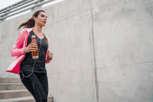 a woman in a pink jacket is running with a bottle of water