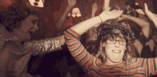 a woman wearing glasses and a striped shirt is dancing at a party