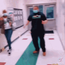 a man wearing a mask is dancing in a hallway next to a woman .