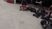 a man sits in front of a row of remote controlled cars with a sign that says landline on it