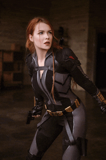 a woman in a black and gray costume holds a gun