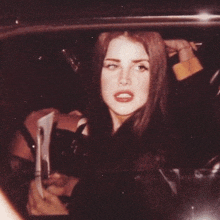 a woman is sitting in the back seat of a car and looking at the camera