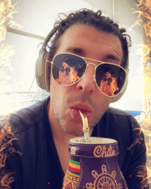 a man wearing sunglasses and headphones is drinking from a purple cup that says chile