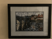 a framed painting shows a bridge over a body of water