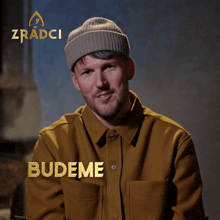 a man wearing a beanie and a brown shirt with budeme mit klid written on it