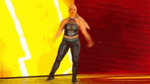 a woman in a wrestling outfit is dancing on a stage in front of a yellow and red background .