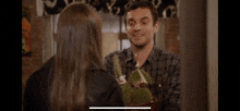 a man is giving a gift to a woman while holding a christmas tree .