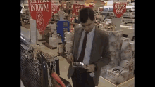 a man in a suit and tie is standing in front of a store with a sign that says best price in town