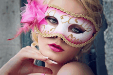 a woman wearing a pink and white mask with feathers on her face