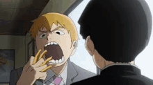 a man in a suit and tie is eating french fries in front of another man .