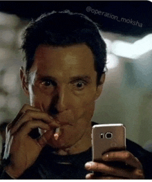 a man is smoking a cigarette while looking at his cell phone