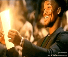 a man in a suit is holding a piece of paper and smiling .