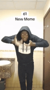 a man wearing a black calvin klein hoodie is standing in front of a bathroom sink
