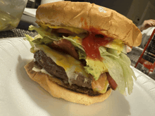 a hamburger with lettuce and tomatoes on a paper plate