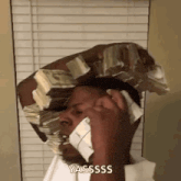 a man is talking on a cell phone while holding a large stack of money on his head .