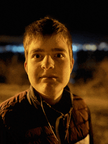 a young man wearing headphones looks at the camera at night