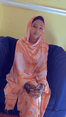 a woman is sitting on a couch wearing an orange and white scarf