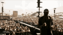 a man in a gas mask stands in front of a crowd at a music festival with the word coachella on the bottom