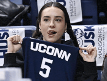 a woman is holding up a uconn jersey number 5