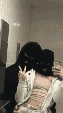 a man and a woman wearing ski masks pose for a picture in a bathroom