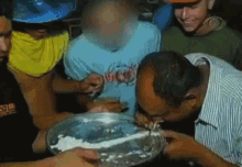 a group of men are sitting around a table and one of them is eating a plate of food .