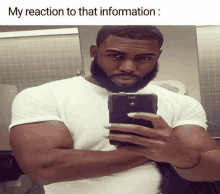 a man with a beard is taking a selfie in a bathroom with the caption " my reaction to that information "