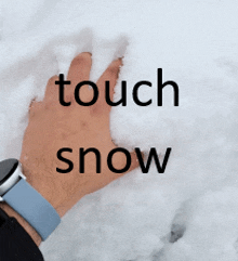 a person 's hand is touching a pile of snow while wearing a watch