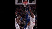 a group of basketball players are playing a game of basketball on a court in front of a crowd .