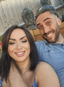 a man and a woman are posing for a picture in front of a statue of a buddha