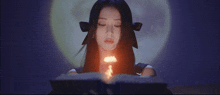 a woman with long black hair is reading a book with a fire coming out of it