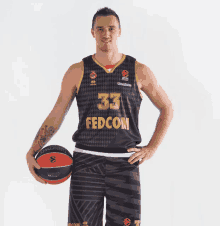 a man wearing a fedcom jersey holds a ball