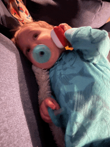 a baby with a pacifier in its mouth is laying on a couch