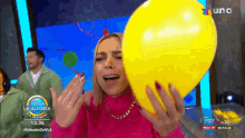 a woman is holding a yellow balloon in front of a screen that says " venga la alegria "