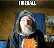 a man with a beard and a hoodie is holding a fireball in his hands .