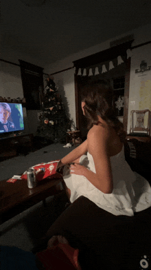 a woman in a white dress is sitting in front of a tv