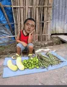 a young boy is sitting in front of a table of vegetables .