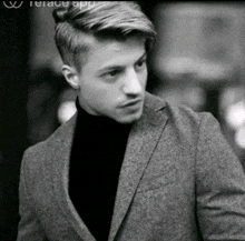 a black and white photo of a man wearing a jacket and turtleneck